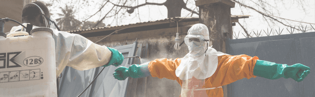 Worker in PPE gets sprayed with disinfectant